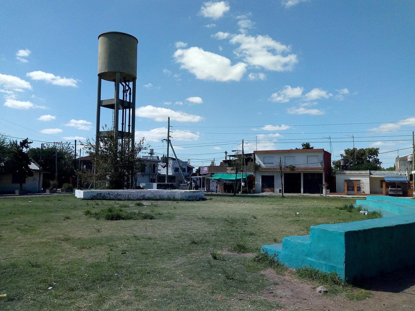 Plaza con césped y un tanque de agua elevado en Gobernador Julio A. Costa