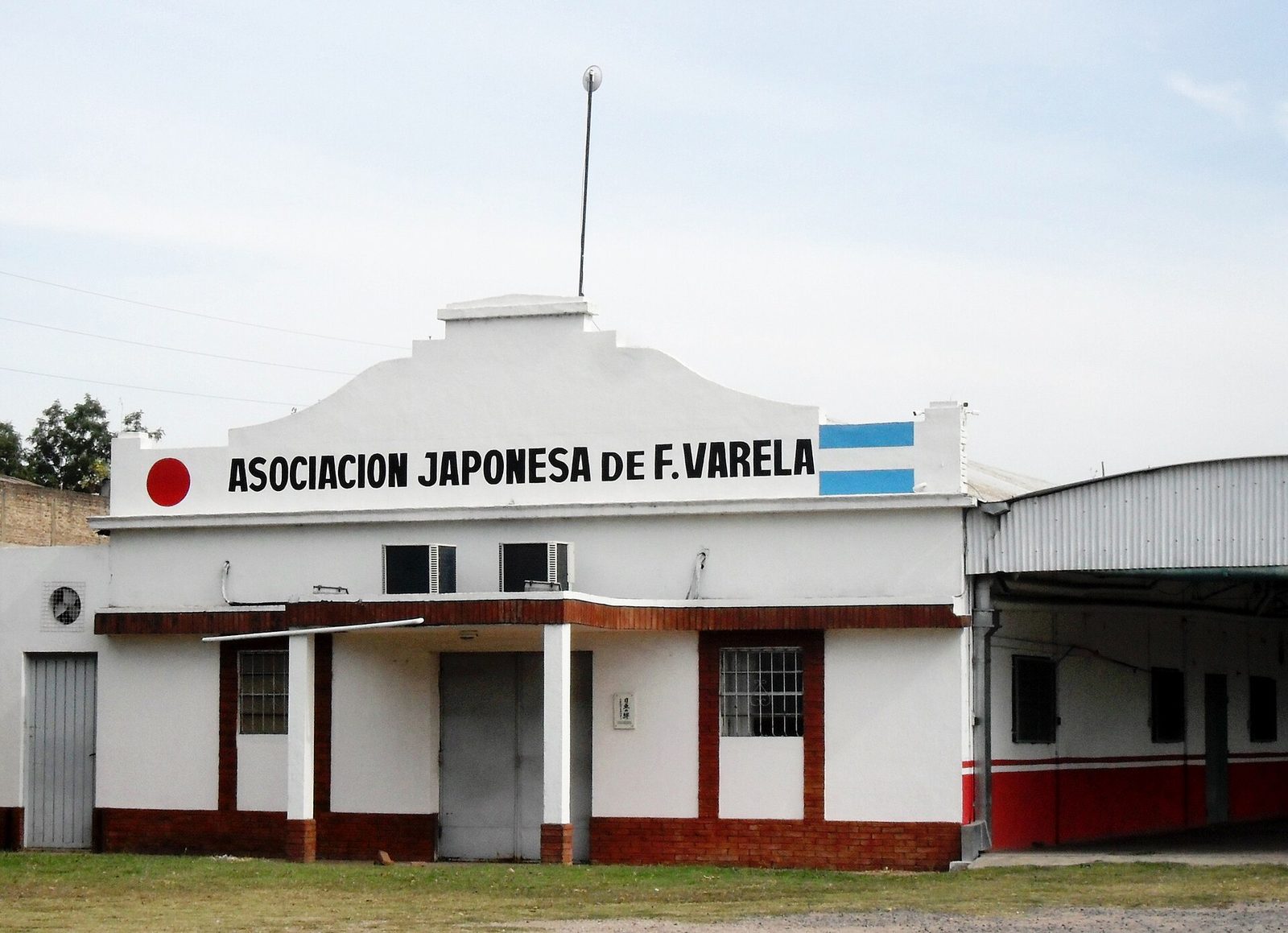Edificio blanco de la Asociación Japonesa de Florencio Varela con banderas pintadas